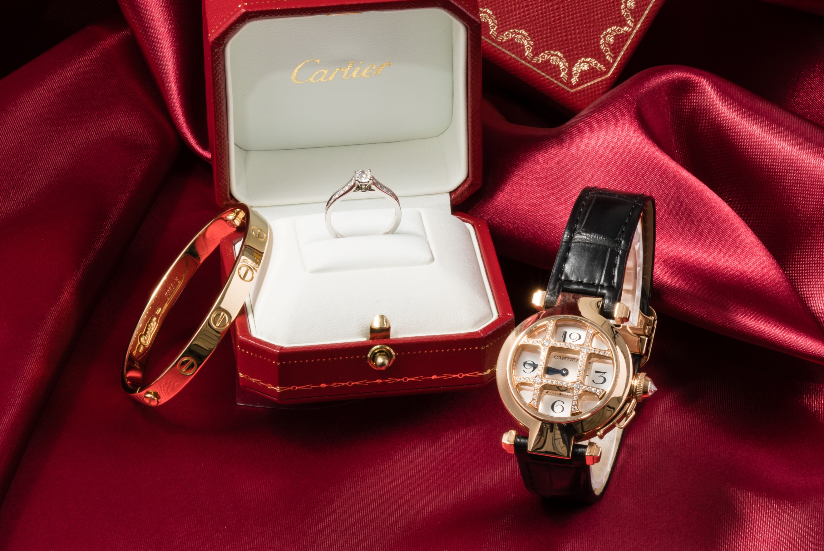 カルティエの赤いジュエリーボックス、保証書、そして美しいレディースウォッチがセットで置かれている。